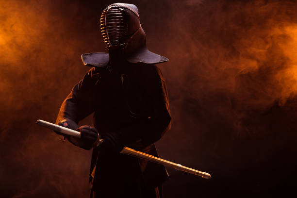 istock Kendo fighter in armor holding bamboo sword in smoke 1150937039