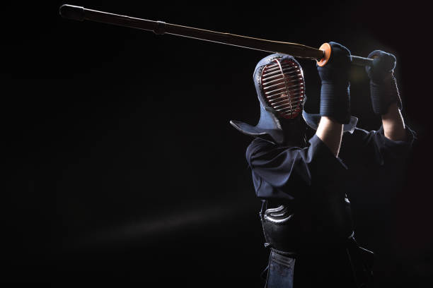 istock Kendo fighter in armor practicing with bamboo sword on black 1150937078