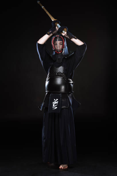 istock Full length view of kendo fighter in armor practicing with bamboo sword on black 1150937108