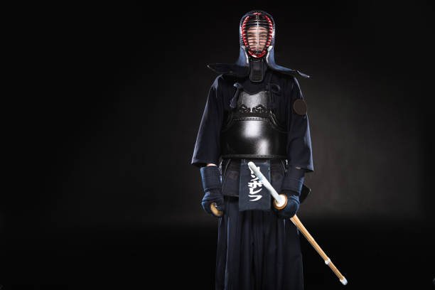 istock Kendo fighter in armor holding bamboo sword on black 1150937125