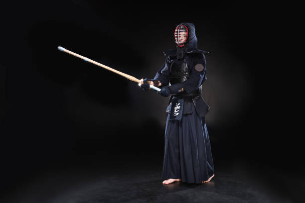 istock Full length view of kendo fighter in armor practicing with bamboo sword on black 1150937132