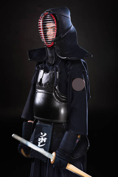 istock Kendo fighter in armor holding bamboo sword on black 1150937133