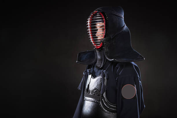 istock Kendo fighter in armor and traditional helmet on black 1150937144