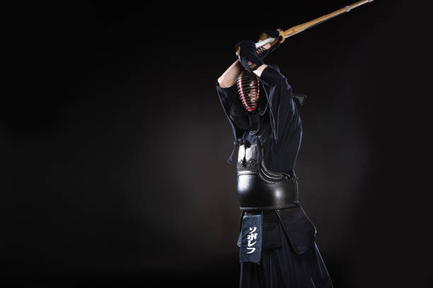 istock Kendo fighter in traditional helmet practicing with bamboo sword on black 1150937156