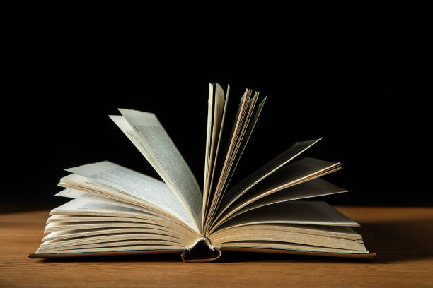 istock open book with white pages on wooden table isolated on black 1150937354