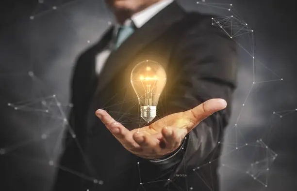 Photo of light bulb with businessman on his hand.