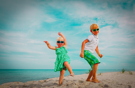 cute happy boy and girl dance at beach, happy kids enjoy vacation at sea