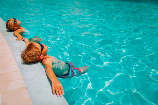 little boy and girl relax in pool, family on beach resort stock photo
