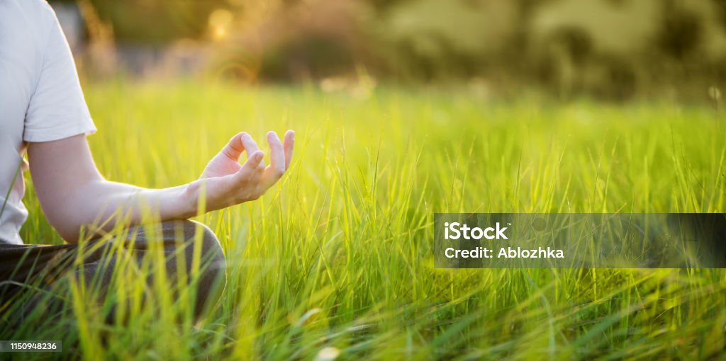 Man is meditating on green grass in the park on sunny summer day. Concept of meditation and healthy lifestyle Man is meditating on green grass in the park on sunny summer day. Concept of meditation and healthy lifestyle with copy space Mental Health Stock Photo