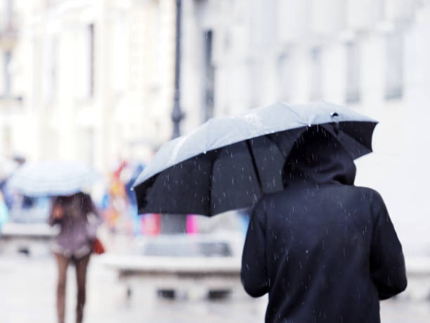 personnes sous des parapluies sur une rue de ville sous la pluie - sweat women wet shirt photos et images de collection