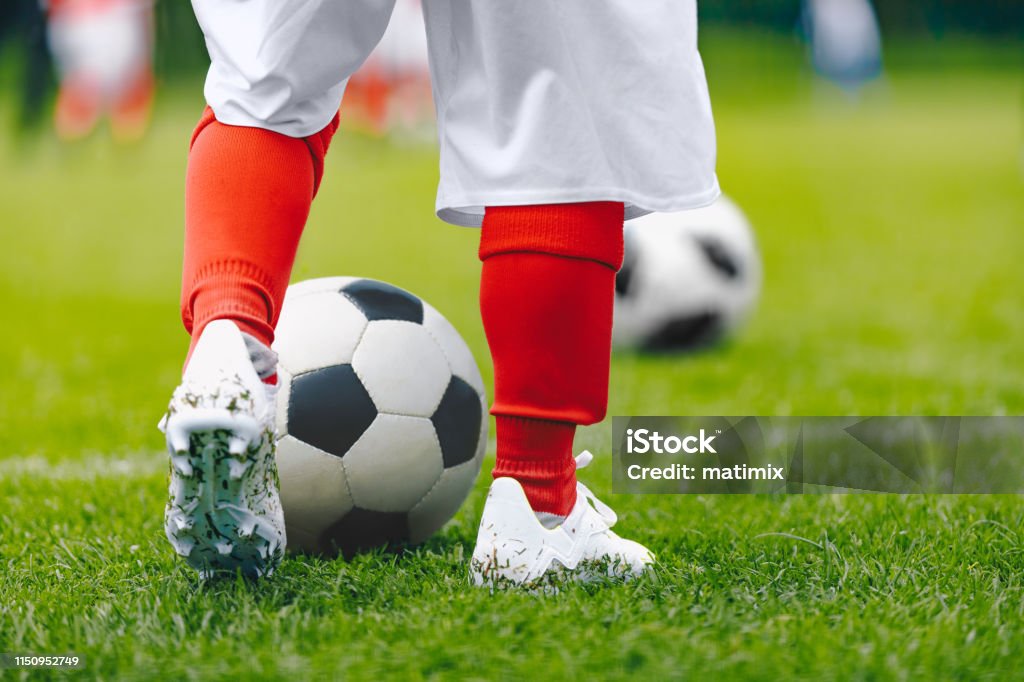 Legs of child in training practice soccer. Kid imprrove dribbling skills on football pitch. Soccer training for children 8-9 Years Stock Photo