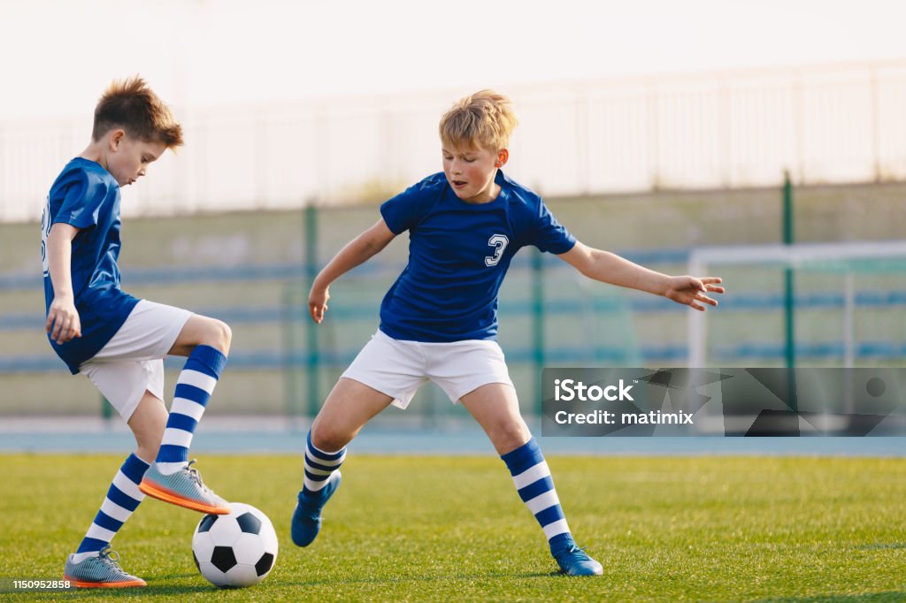 Two Junior Soccer Players Training with Soccer Ball on Stadium Grass Pitch Child Stock Photo