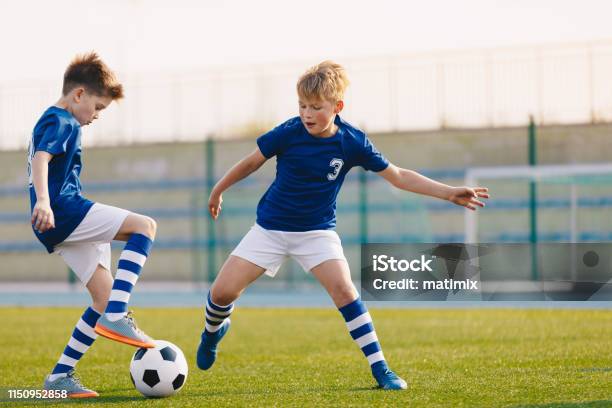 Two Junior Soccer Players Training With Soccer Ball On Stadium Grass Pitch Stock Photo - Download Image Now