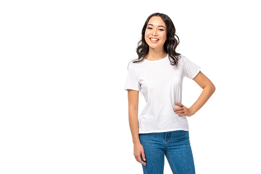 Attractive asian female in white t-shirt and blue jeans holding hand on hip isolated on white
