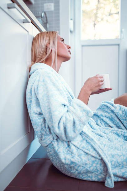istock Female Sitting On The Floor In Pegnoir And Drinking Coffee 1150954237