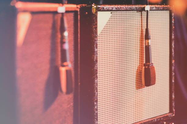 Large guitar amplifier and loudspeaker box on stage with additional microphone