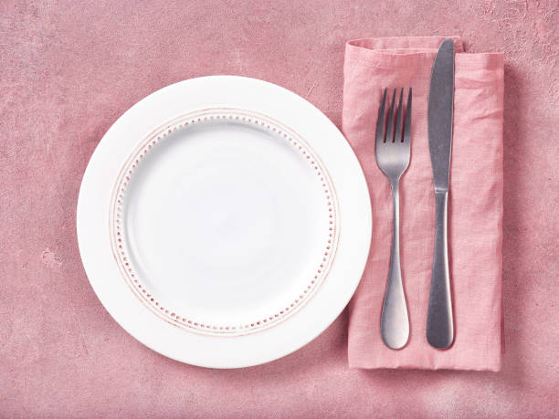 istock Empty plate, cutlery and napkin on pink concrete background 1150955183