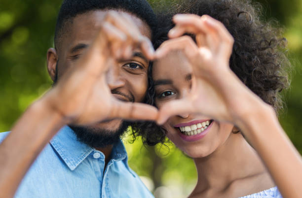 istock Cute couple making heart shape in park 1150964393