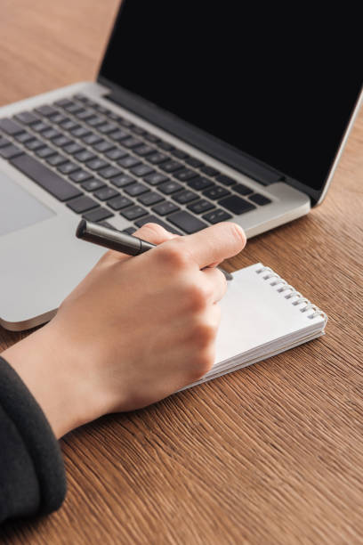 istock Partial view of girl writing in notebook at workplace 1150964989