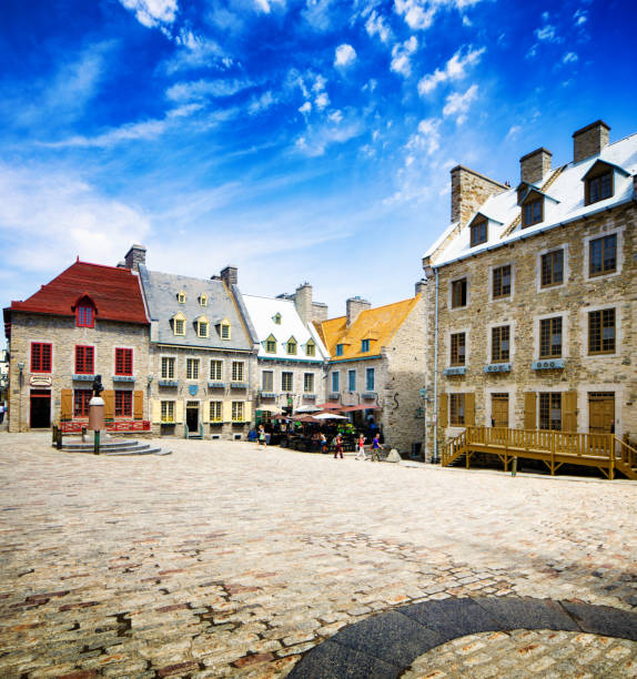 Quebec City Place Royale on a sunny Spring day looking towards old buildings, cafes and stores. A few people populate the image.