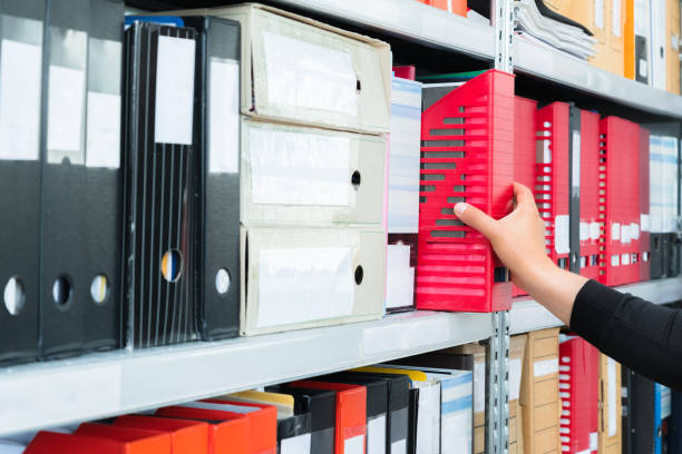 istock Mans hand picking a blank blind folder with files from the shelf. Archival, stacks of documents at the office or library 1150971267