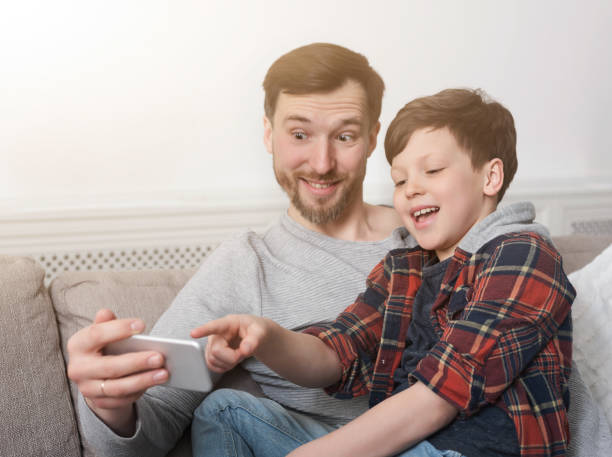 Funny father and his son taking selfie at home