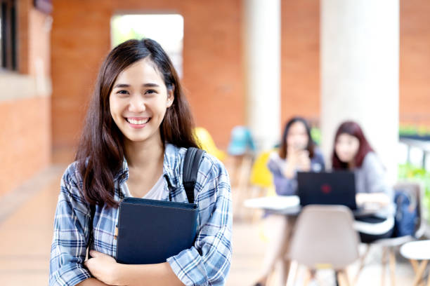 foto de la cabeza de joven feliz estudiante asiático sonriendo y mirando a la cámara con amigos en el fondo de la universidad al aire libre. mujer asiática en la educación futura o el concepto de aprendizaje personalizado. - college girl fotografías e imágenes de stock