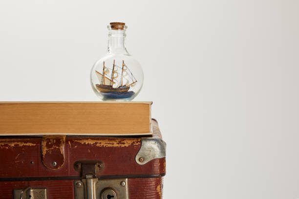 istock toy ship in glass bottle and book on brown suitcase with copy space 1150975878