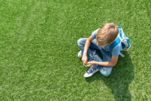 malheureux triste garçon bouleversé assis seul sur l’herbe - pre teen boy photos et images de collection