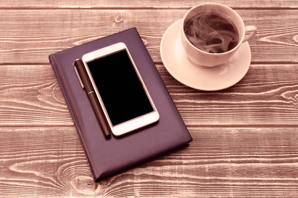 diary, pen, smartphone with black screen, a Cup of coffee on a wooden background. business planning.