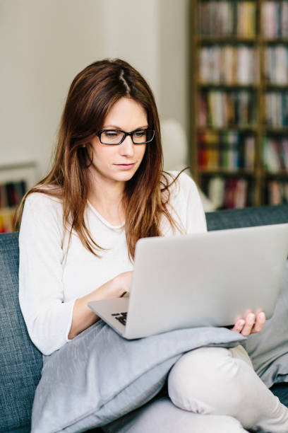 istock young woman sit on sofa and use laptop at home 1150979992