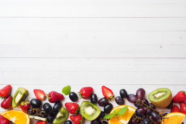 istock Fresh fruit strawberry kiwi grapes on white table with copy space. 1150980463