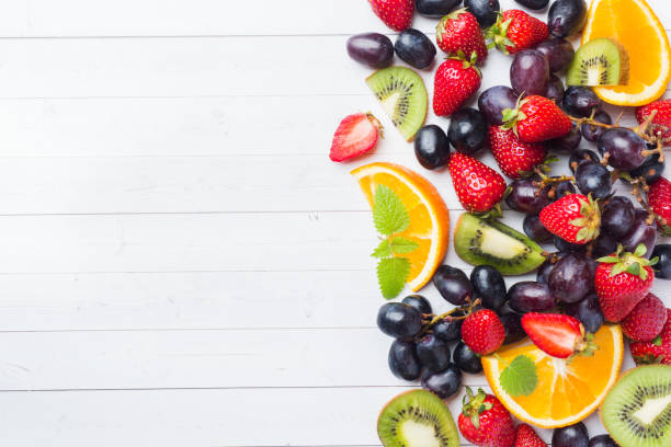 istock Fresh fruit strawberry kiwi grapes on white table with copy space. 1150980473