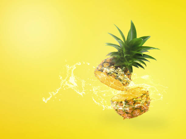 istock Water Splashing on Fresh Pineapple is tropical fruit isolated on yellow background. 1150981381