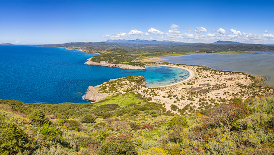 Panoramic aerial view of voidokilia beach, one of the best beaches in mediterranean Europe. Seen from from the Palaiokastro. Voidokilia Beach is a popular beach in Messinia in the Mediterranean area. In the shape of the Greek letter omega (Ω), its sand forms a semicircular strip of dunes. On the land-facing side of the strip of dunes is Gialova Lagoon, an important bird habitat. The beach has been named \