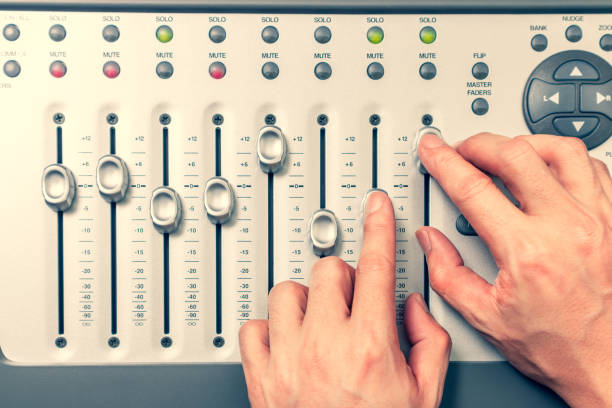 le mani dell'ingegnere del suono regolano il fader del livello del volume sulla console di miscelazione digitale. produzione musicale, registrazione, trasmissione, concetto musicale - human finger sound mixer music producer foto e immagini stock