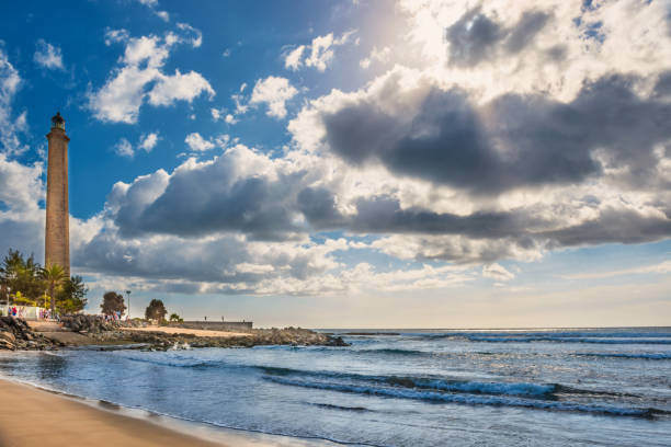 View of sea, sky with clouds and Maspalomas lighthouse View of sea bay, sky with clouds and Maspalomas lighthouse at bright day. Gran Canaria, Spain lighthouse lighting equipment reflection rock stock pictures, royalty-free photos & images