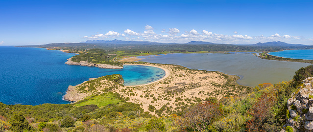 Panoramic aerial view of voidokilia beach, one of the best beaches in mediterranean Europe. Seen from from the Palaiokastro. Voidokilia Beach is a popular beach in Messinia in the Mediterranean area. In the shape of the Greek letter omega (Ω), its sand forms a semicircular strip of dunes. On the land-facing side of the strip of dunes is Gialova Lagoon, an important bird habitat. The beach has been named \