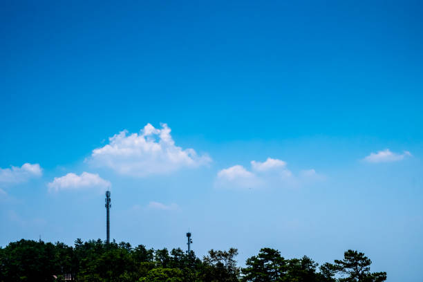 forêt verte d'arbre et tours de télécommunication contre le ciel bleu clair avec les nuages pelucheux blancs. - sky tree audio photos et images de collection