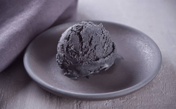 istock Black ice cream on a black ceramic plate with gray napkin on a gray table 1150988935