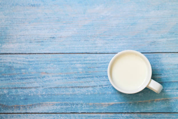 istock White cup with milk on a blue wooden table. 1150991063