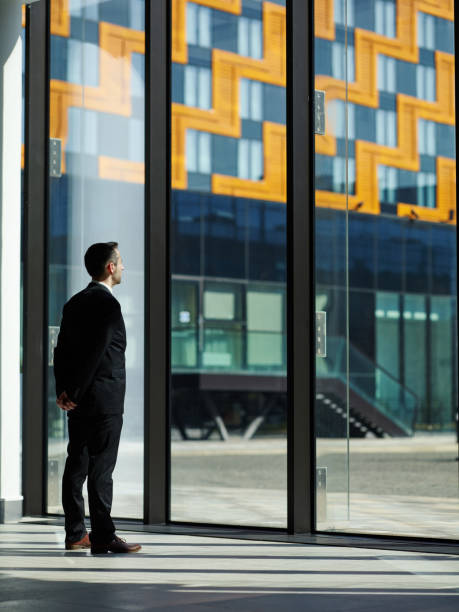 istock Confident manager in formal suit standing in office lobby with hand behind back and looking through window waiting for somebody to come 1150997219