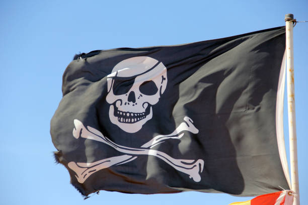 istock Pirate flag flying against a blue sky background 1150999490