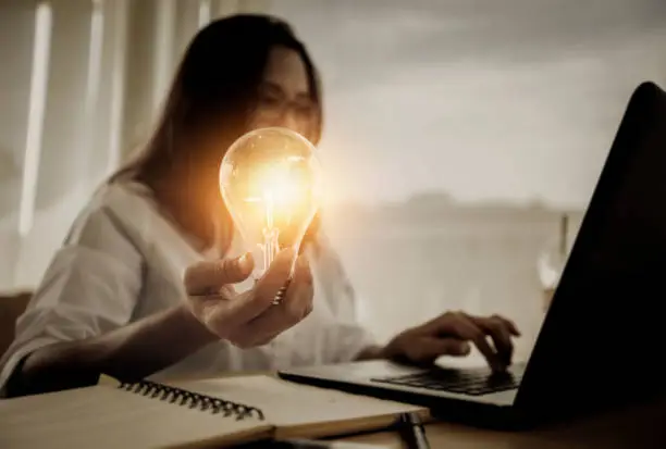 Business women hand holding light bulb, concept of new ideas with innovation and creativity