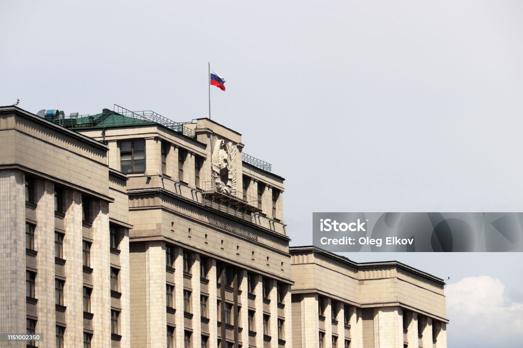 Russian flag on the Parliament building in Moscow on sky background Facade of State Duma of Russia with soviet coat of arms, russian authority State Duma Stock Photo