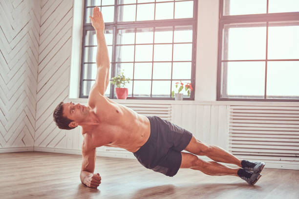 istock Handsome shirtless muscular man doing functional exercises on floor at home. 1151002749