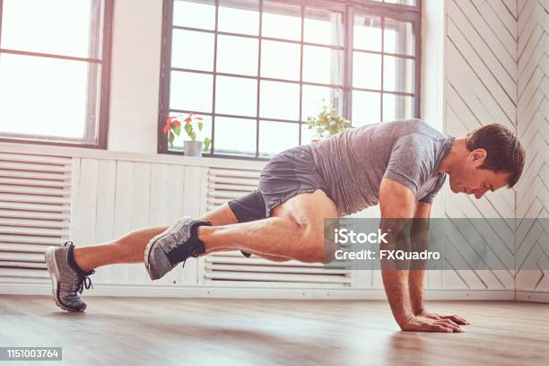 Hombre Musculoso Guapo En Una Camiseta Y Shorts Haciendo Ejercicios Funcionales En El Piso En Casa Foto de stock y más banco de imágenes de Ejercicio físico