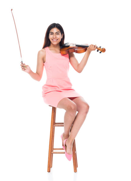 istock Attractive young latino female playing the violin while sitting on stool 1151003981