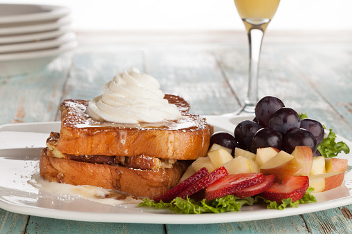 french toast breakfast with whipped cream and fruit salad, and champagne