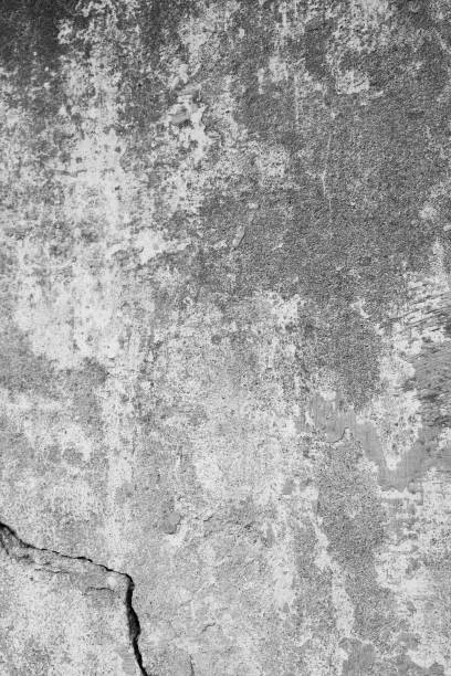 istock Dirty, old stone wall with rough and cracked structures. At the bottom right, a strong crack in the wall. Concrete wall background in portrait format, in industrial design. 1151011018